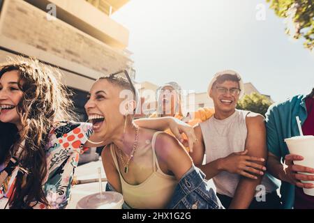 Profiter de l'amitié et de la jeunesse. Groupe de la génération z amis riant gaiement tout en marchant ensemble dans le soleil d'été. De jeunes amis heureux Banque D'Images
