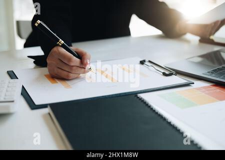 Gros plan d'une femme d'affaires tenant un stylo et pointant vers la fiche d'information sur son bureau, lisant les données financières de l'entreprise pour faire un plan financier Banque D'Images