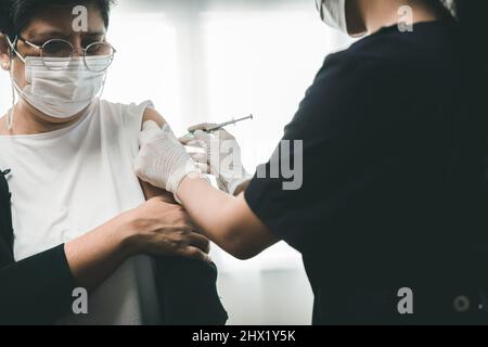 Vieille femme asiatique vaccine avec un médecin donnant la dose à un patient âgé, concept d'injection de vaccin Covid-19 Banque D'Images