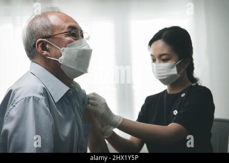Vieil homme asiatique vacciné avec la femme médecin, donnant la dose à un patient âgé, concept d'injection de vaccin Covid-19 Banque D'Images