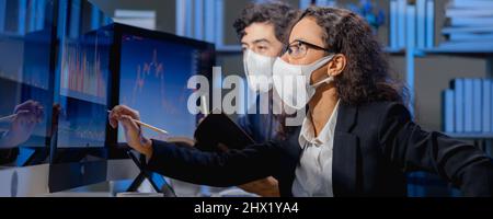 les courtiers d'équipe portant un masque de visage regardent le graphique du marché boursier sur l'ordinateur de moniteur pour analyser avant l'offre et organise les transactions entre l'acheteur et la vente Banque D'Images