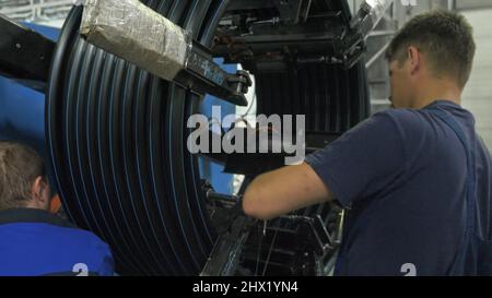 RUSSIE, ANGARSK - 8 JUIN 2018 : tuyau de bobine de filetage de rouleau. Fabrication de tuyaux d'eau en plastique à l'usine. Procédé de fabrication de tubes en plastique sur la machine-outil avec l'utilisation d'eau et de pression d'air. Banque D'Images