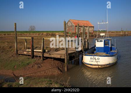 Un bateau de pêche amarré au quai par l'ancienne Barn de charbon dans le port de North Norfolk à Thornham, Norfolk, Angleterre, Royaume-Uni. Banque D'Images