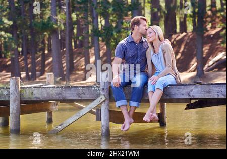 Partager un moment romantique. Un couple marié aimant appréciant un moment sur la jetée au lac. Banque D'Images