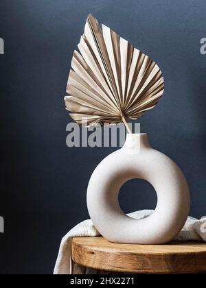 Vase rond élégant en céramique avec feuilles de palmier séchées. Arrière-plan bleu foncé. Vue avant. Copier l'espace Banque D'Images
