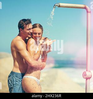 Vous êtes censé me laver. Photo courte d'un jeune couple affectueux qui se délecte sur la plage. Banque D'Images