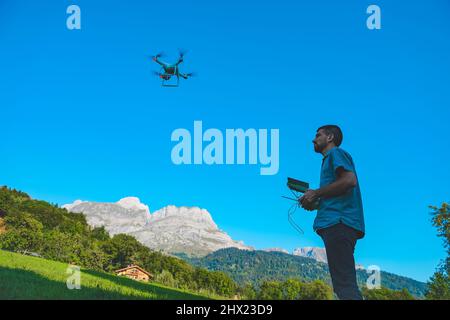 Jeune homme volant drone sur un paysage de montagne étonnant. Homme utilisant un drone avec télécommande pour prendre des photos et des vidéos aériennes. Banque D'Images