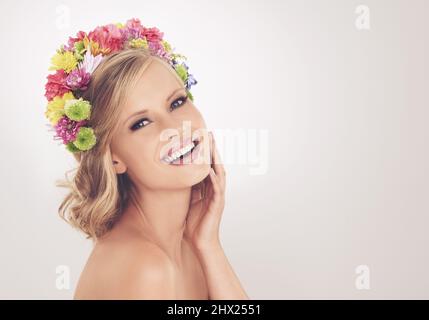 Porter la seule couronne pour une déesse printanière. Une jeune femme avec un arrangement de fleur dans ses cheveux souriant à la caméra. Banque D'Images