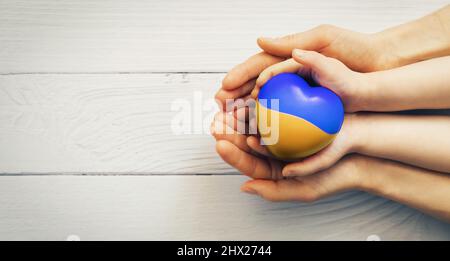 Soutenir l'Ukraine - les mains de la mère et de l'enfant tenant le coeur. Don et concept de charité. Espace de copie Banque D'Images