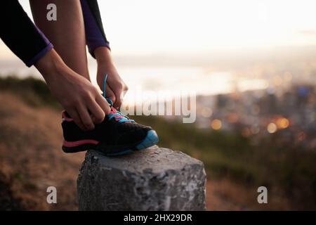 Se sentir bien et garder la forme. Coupe courte d'un coureur qui fixe ses lacets. Banque D'Images