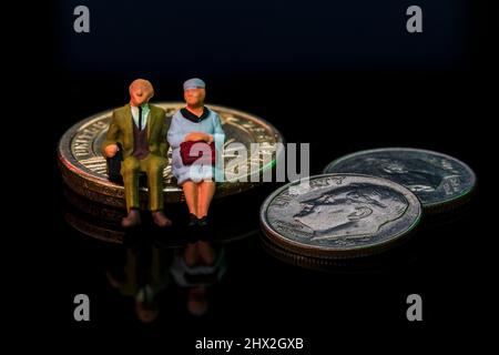 Couple âgé âge d'or inflation Pensions assis coin pile miniature personnes Figures Copy Space fond noir Banque D'Images