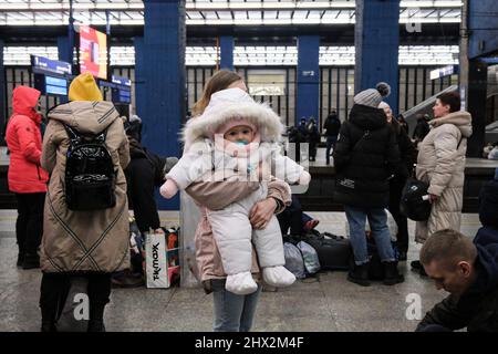 Une femme porte son bébé dans les bras à la plate-forme de la gare centrale de Varsovie, en attendant le transit vers d'autres villes et pays pour s'installer. Alors que la crise de guerre se poursuit en Ukraine, des millions d'Ukrainiens ont fui leur pays d'origine vers la Pologne, la plupart d'entre eux étant des femmes et des enfants. La plupart d'entre eux se reposent temporairement dans les gares de Varsovie et attendent de s'installer. Selon l'agence de l'ONU, le nombre de migrations de réfugiés a atteint 1,5 millions, ce qui est le plus rapide depuis la deuxième Guerre mondiale. Le gouvernement polonais a annoncé un plan de 8 milliards z Banque D'Images