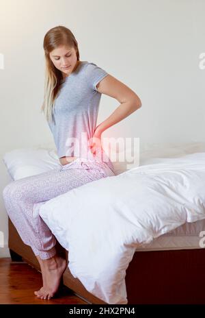 J’ai besoin d’examiner cette douleur. Prise de vue d'une jeune femme souffrant de douleurs dorsales, mise en évidence en rouge éclatant. Banque D'Images