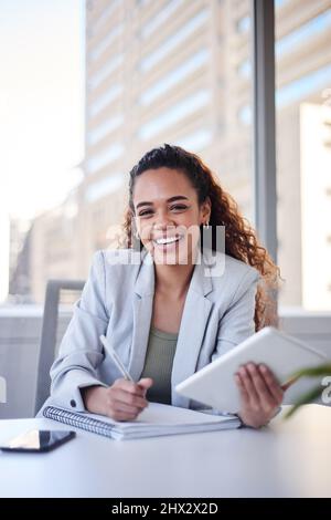 Portrait d'une jeune femme au bureau de la ville souriant avec une tablette et un ordinateur portable Banque D'Images