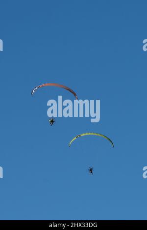 Deux parapentes propulsés dans les airs en hiver au-dessus de South Padre Island, Texas. Sur un parapente motorisé, le pilote porte un moteur de sac à dos. Banque D'Images