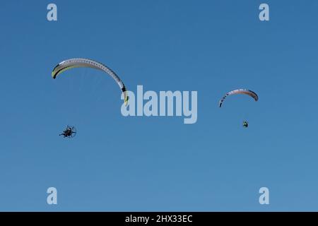 Deux parapentes propulsés dans les airs en hiver au-dessus de South Padre Island, Texas. Sur un parapente motorisé, le pilote porte un moteur de sac à dos. Banque D'Images