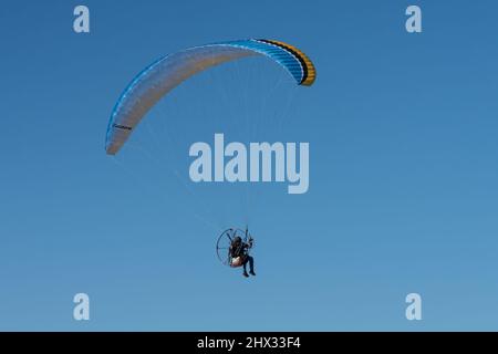 Un parapente motorisé dans les airs en hiver au-dessus de l'île de South Padre, Texas. Sur un parapente motorisé, le pilote porte un moteur de sac à dos. Banque D'Images
