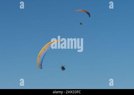 Deux parapentes propulsés dans les airs en hiver au-dessus de South Padre Island, Texas. Sur un parapente motorisé, le pilote porte un moteur de sac à dos. Banque D'Images