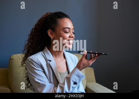 Une jeune femme d'affaires envoie une note vocale à un collègue Banque D'Images