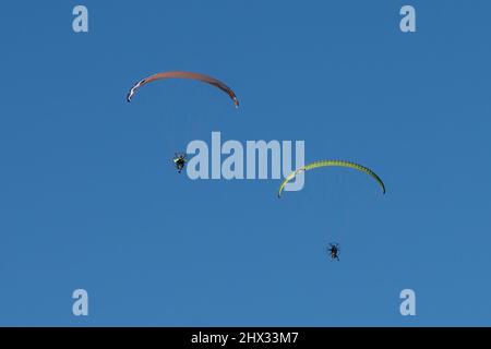 Deux parapentes propulsés dans les airs en hiver au-dessus de South Padre Island, Texas. Sur un parapente motorisé, le pilote porte un moteur de sac à dos. Banque D'Images