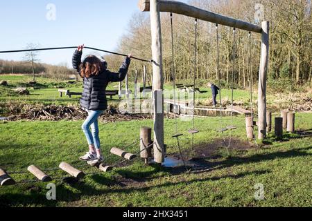 Une jeune fille joue sur un parcours d'obstacles dans un parc, sous le soleil de Bright Spring, dans une forêt à Diemen, aux pays-Bas. Banque D'Images