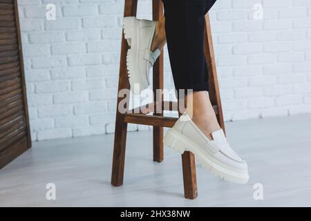 Jambes d'une jeune belle femme en pantalon noir et mocassins modernes en cuir blanc. Nouvelle collection de chaussures pour femmes printemps-été 2022 Banque D'Images