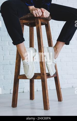 Jambes d'une jeune belle femme en pantalon noir et mocassins modernes en cuir blanc. Nouvelle collection de chaussures pour femmes printemps-été 2022 Banque D'Images