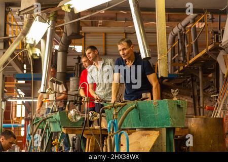 Beryozauka, Bélarus - 07 mars 2022 : une équipe de souffleurs en verre travaille à la fabrication de vases et de lunettes en verre. Jusqu'à 20 travailleurs peuvent être impliqués Banque D'Images