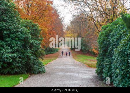 Trois personnes marchant le long de la large promenade, un long chemin droit dans les jardins de Tatton Park près de Knutsford dans Cheshire Banque D'Images