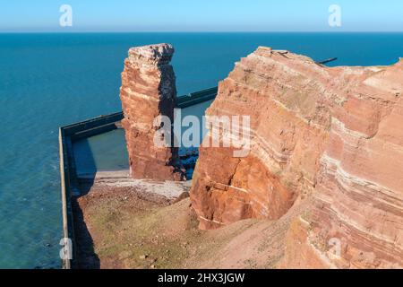 Lange Anna pile de mer et de hautes falaises rouges spectaculaires de l'île d'Heligoland avec mer rugueuse. Jour d'hiver ensoleillé et venteux à Helgoland, en mer du Nord, en Allemagne. Banque D'Images