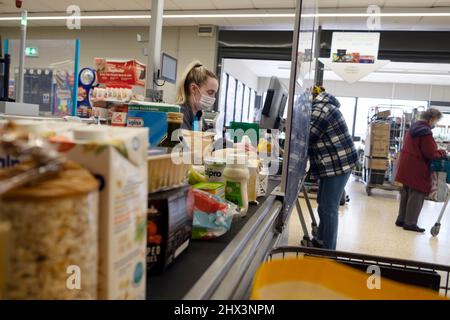 Coût de la vie nourriture épicerie au comptoir de caisse Co Op ouvrier de supermarché femme travaillant à la caisse client portant le masque Covid pays de Galles 2022 KATHY DEWITT Banque D'Images