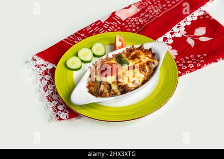 Un plat grec moussaka avec salade dans un plat isolé sur une nappe colorée vue sur le dessus sur fond gris Banque D'Images