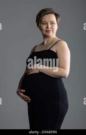 Portrait de la femme enceinte sur son troisième trimestre, deux semaines avant l'accouchement, faisant séance photo en studio Banque D'Images