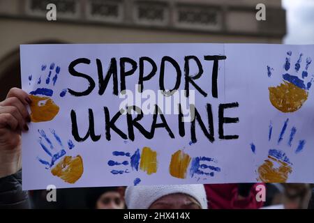 Bannière faite à la main avec slogan SOUTIEN UKRAINE et mains peintes aux couleurs nationales ukrainiennes tenues par le manifestant pendant la démonstartion pour soutenir l'Ukraine Banque D'Images