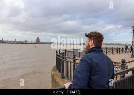 Jeune homme avec des cheveux fabuleux donnant sur la mer, en regardant vers Wirral de Liverpool Banque D'Images