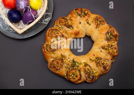 Rouleau de Pâques avec noix et œufs colorés dans un panier en forme de cœur. Arrière-plan marron... Banque D'Images