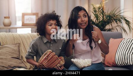 Ce match nous a au bord de nos sièges. Prise de vue d'un adorable petit garçon regardant un match de baseball avec sa mère à la télévision à la maison. Banque D'Images