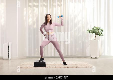 Belle jeune femme s'exerçant pas aérobie à la maison Banque D'Images