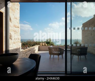 Intérieur depuis l'espace salle à manger donnant sur de grandes portes coulissantes donnant sur une terrasse privée et une plate-forme d'observation. Clifftops, Dorset, Portland, Royaume-Uni. Banque D'Images