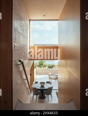 Vue intérieure de l'espace double hauteur depuis le haut d'un escalier, donnant sur la salle à manger et dehors sur la terrasse extérieure, détails de poli Banque D'Images