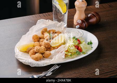 Moules frites croustillantes en pâte avec citron, sauce et salade Banque D'Images