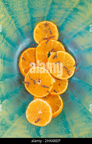 Tranches d'orange mandarin sur une soucoupe à motif radial bleu. Toile de fond du produit. Banque D'Images