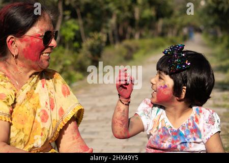 Dame et enfant indiens âgés appréciant Holi avec Gulal ou Abir Rang Abeer. Fête, famille, plaisir, fête, plaisir, Ensemble, multi-génération, Banque D'Images