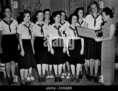 Les filles américaines de feu de camp présentent un cadeau à Mme. Chiang -- les membres du chapitre Mei-ling de l'American Camp Fire Girls regardent leur président, Marjorie Holterman, 15 ans, présente à Mme. Chiang Kai Shek, épouse du généralissime chinois, un portefeuille contenant, une trace de Gimp feu les domations de filles à l'aide de guerre chinoise. Les filles, qui ont nommé leur chapitre en l'honneur de Mme Chiang, lui ont également donné un fonds pour la prise en charge de deux orphelins de guerre chinois et une lettre de camaraderie aux jeunes Chinois. 22 août 1943. (Photo par U.S. Office of War information photo). Banque D'Images