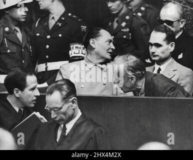 Les criminels de guerre nazis chuchotent sur le quai de Nuremberg. Joachim von Ribbentrop penche devant Rudolf Hess pour s'entretenir avec son avocat (en bas à gauche), whille Hermann Goring (au centre), se tourne pour parler à Karl Dontiz (en arrière à droite). L'essai continue de traîner. 18 avril 1946. (Photo par photo de presse associée). Banque D'Images