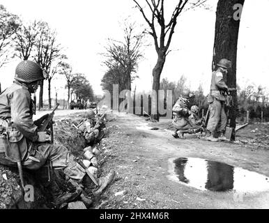 Les alliés se déplacent sur Munster les soldats de la 17th U.S. Airborne Division attendent des ordres d'avance sur Munster, ville de Reich à 51 miles au nord-est du Rhin de Wesel, Qui est entré par des chars de la Sixième Coldstream Guards britannique, dont certains peuvent être vus roulant le long de l'autoroute (à gauche). Le point fort allemand a été effacé le 3 avril 1945 par les troupes alliées qui comprenaient des éléments de la neuvième armée américaine. 21 mai 1945. (Photo par U.S. signal corps photo). Banque D'Images