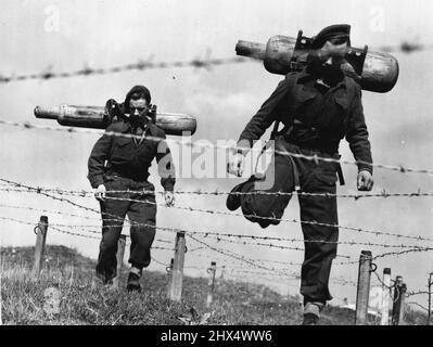 Ils sont sur Une route permanente Mars - l'armée teste l'équipement pour ACTIC et Tropiques -- les troupes transportant des bouteilles de gaz factices grimpent le fil barbelé sur le cours de combat à Hoath Lane, Gillingham, près de Chatham, Kent, comme ils testent l'équipement de l'Armée. Trente hommes ayant le travail le moins enviable de l'Armée de terre sont sur une route « permanente » qui marchent sur le terrain d'essai de l'Armée britannique, rattaché au centre d'essais sur le terrain de cette base de Kentish Navel. Chaque jour, ils s'enroulent de huit à 12 miles sur des pavés, des rochers et du sable d'un parcours de 600 yards pour mettre les bottes de l'Armée de terre à travers leur test de « passage » de 350 miles. 7 avril 1948. Banque D'Images