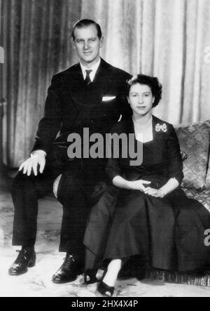 Couple Royal - Eve of Royal Tour Study -- Une nouvelle étude de la princesse Elizabeth et du duc d'Édimbourg, réalisée par Baron dans le salon de leur résidence de Londres, Clarence House. La princesse porte une soie figurée bleu de l'après-midi avec encolure carrée et corsage croisé. La jupe est extrêmement rigide sous-jupe. Le cadeau de mariage en forme d'arc de la reine Marie. Avec le duc, qui est vu ici portant une cravate de la marine royale avec un costume-lounge bleu marine, la princesse quittera l'Angleterre le 31 janvier pour commencer leur visite royale de l'Australie et de la Nouvelle-Zélande. 21 janvier 1952. Banque D'Images