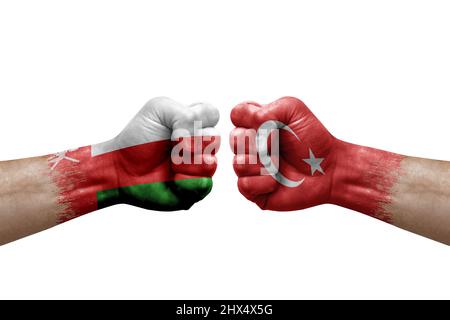 Deux mains poinçonner l'une à l'autre sur fond blanc. Les drapeaux de pays ont peint des poings, le concept de crise de conflit entre oman et la turquie Banque D'Images