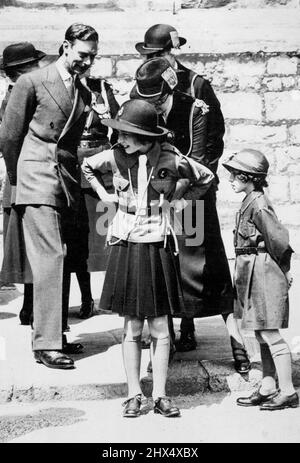 Inspection des Guides à Windsor Un événement charmant au cours du passé de mars des Guides. Sur la photo, la princesse Elizabeth est en train de régler la ceinture de son uniforme. Sa Majesté le roi George VI est à la recherche. La princesse Margaret est vue à droite dans l'uniforme Brownie. C'est la première fois que les Princesses assistent à une fonction dans leur uniforme de Guides. 11 juillet 1938. Banque D'Images